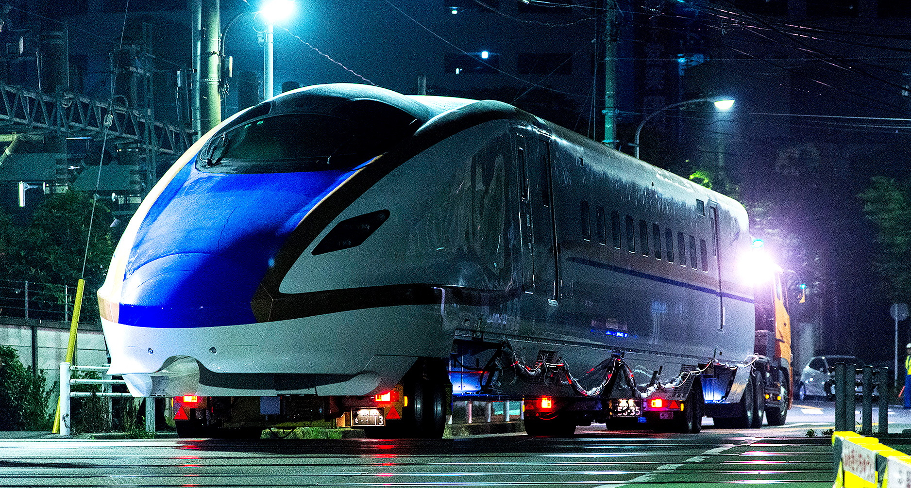 2車線の狭い踏切を渡る北陸新幹線先頭車両
